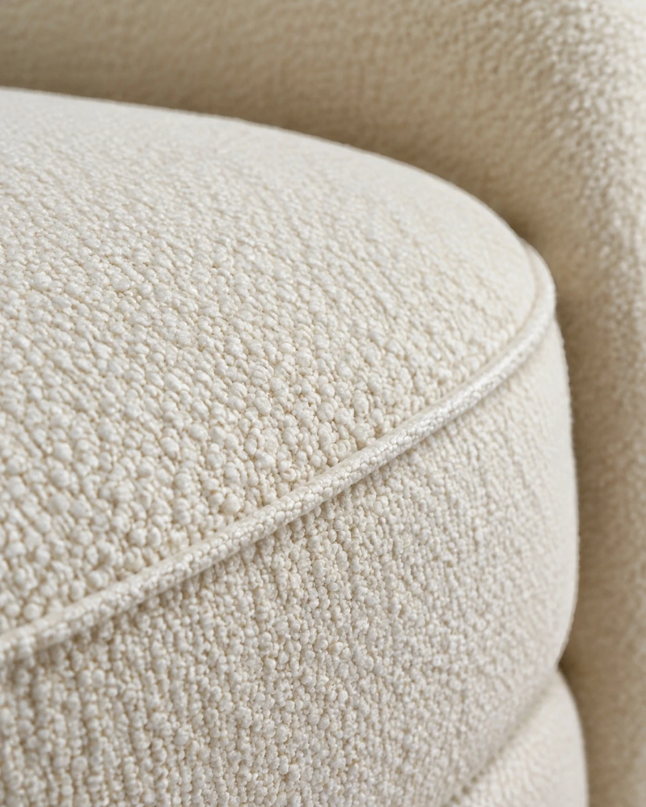 Macro of ivory bouclé upholstery with a piped seam